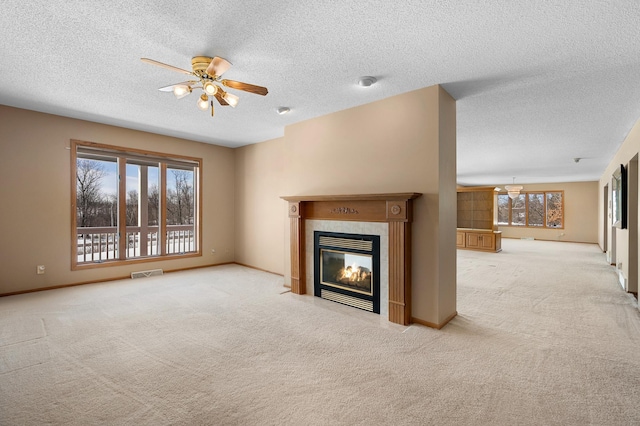 unfurnished living room with visible vents, plenty of natural light, carpet, and a premium fireplace