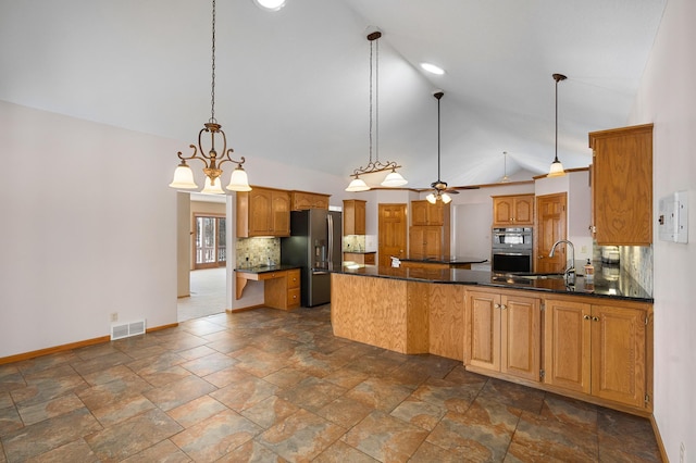 kitchen with dark countertops, decorative backsplash, a peninsula, and stainless steel appliances