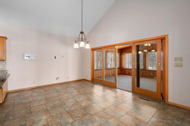 empty room featuring baseboards and high vaulted ceiling