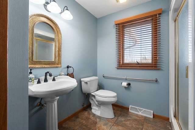 bathroom with baseboards, visible vents, a stall shower, a sink, and toilet