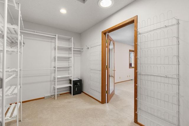 walk in closet featuring light colored carpet