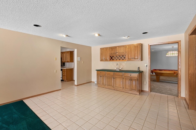 kitchen with light tile patterned floors, baseboards, dark countertops, and a sink