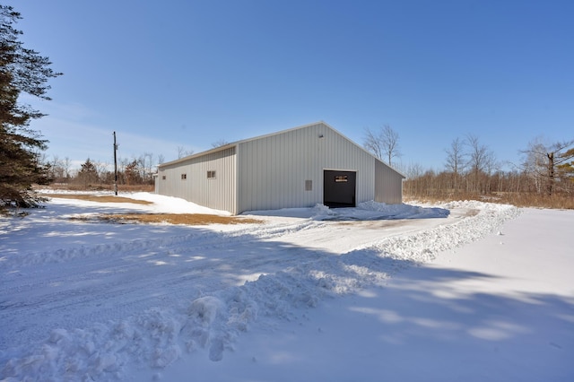 snow covered structure featuring an outbuilding and an outdoor structure