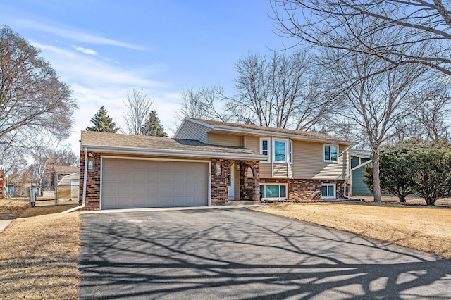 tri-level home with brick siding, fence, aphalt driveway, a front yard, and a garage