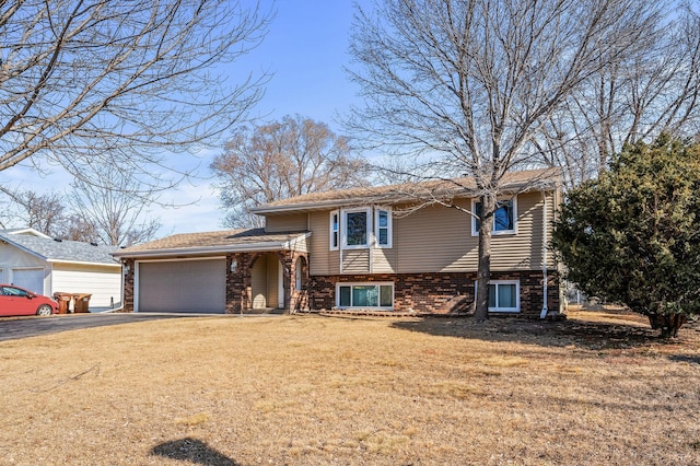 tri-level home featuring brick siding, a garage, a front lawn, and driveway