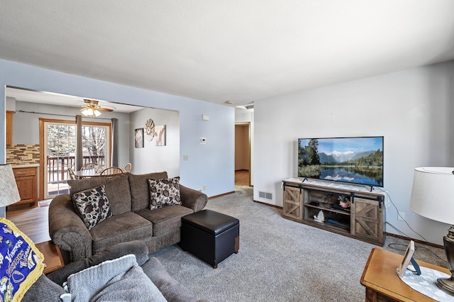 living room featuring a ceiling fan, baseboards, visible vents, and carpet floors