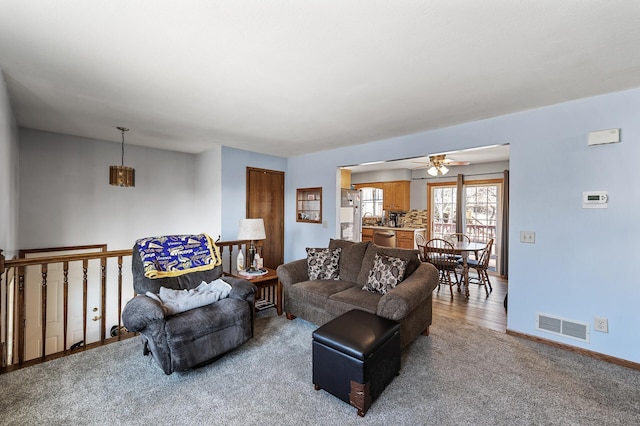 living area with carpet flooring, baseboards, visible vents, and ceiling fan