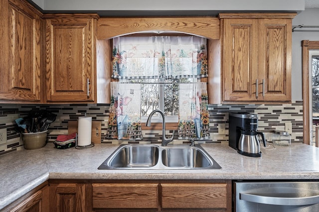 kitchen with a sink, stainless steel dishwasher, and brown cabinetry