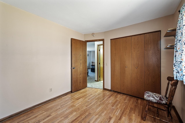 unfurnished bedroom featuring a closet, light wood-type flooring, and baseboards