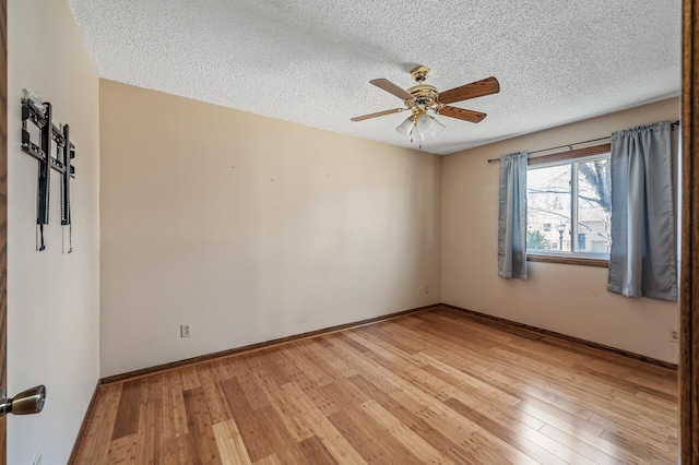 spare room with baseboards, a textured ceiling, a ceiling fan, and light wood-style floors