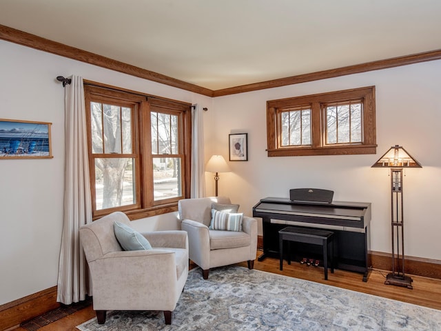 living area with ornamental molding, baseboards, and wood finished floors