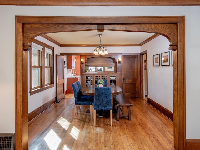 dining area featuring visible vents, baseboards, light wood-style flooring, arched walkways, and crown molding