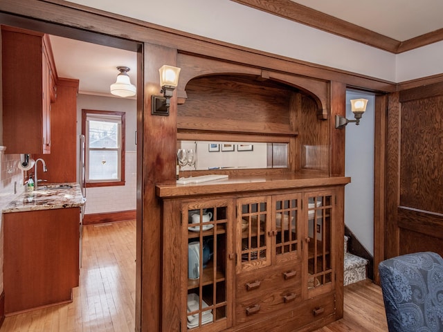 interior space with a sink, wood finished floors, baseboards, and ornamental molding