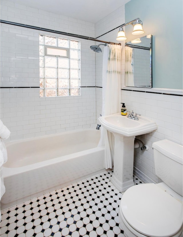 full bath with toilet, tile walls, and shower / tub combo with curtain