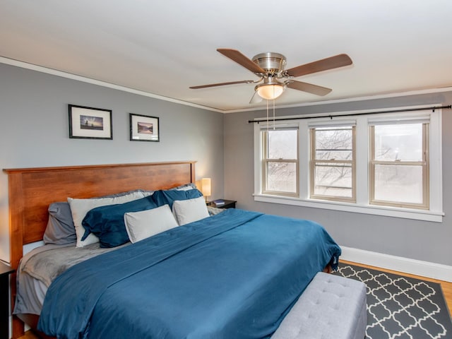 bedroom with a ceiling fan, crown molding, baseboards, and wood finished floors