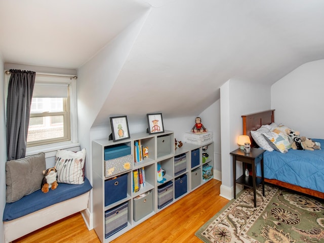 bedroom featuring light wood-type flooring, lofted ceiling, and baseboards