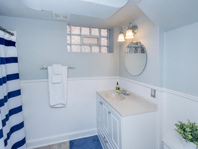 bathroom featuring visible vents, a wainscoted wall, toilet, a shower with shower curtain, and vanity