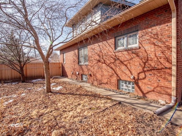 view of property exterior with brick siding and fence