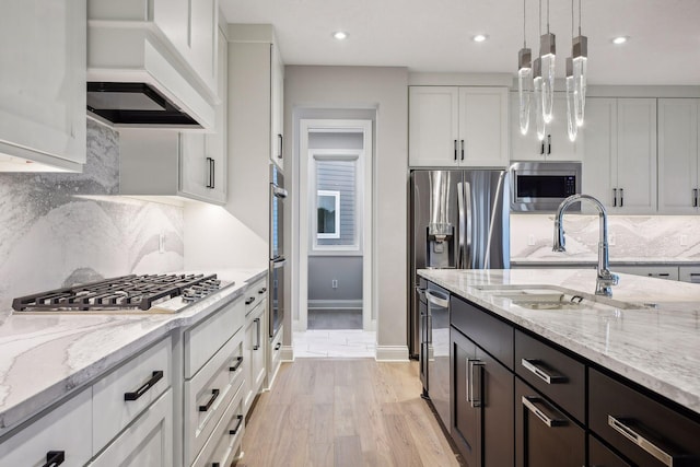 kitchen featuring light wood-style flooring, a sink, white cabinetry, appliances with stainless steel finishes, and custom exhaust hood