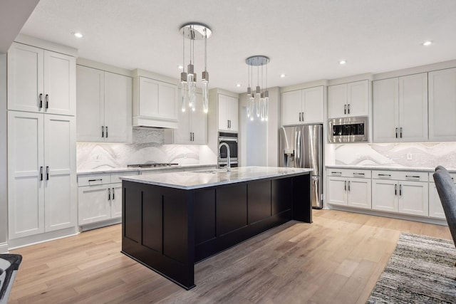 kitchen with stainless steel appliances, light wood-style flooring, white cabinets, and hanging light fixtures