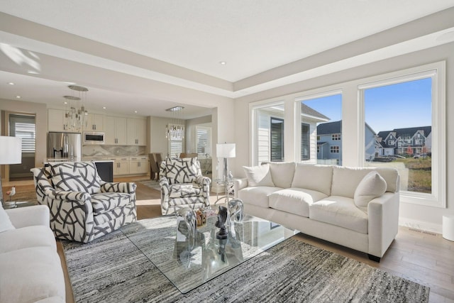 living room featuring an inviting chandelier, recessed lighting, baseboards, and light wood-type flooring