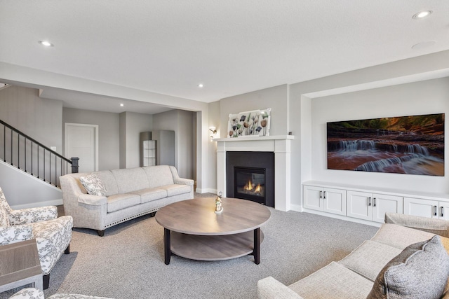 living room featuring recessed lighting, stairway, a glass covered fireplace, and carpet flooring