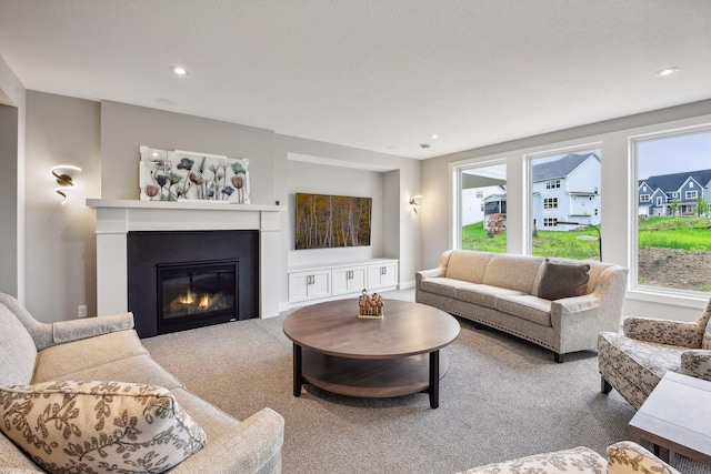 living area featuring a glass covered fireplace, plenty of natural light, carpet flooring, and recessed lighting