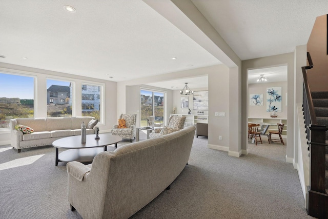 living room featuring stairway, baseboards, carpet, and a healthy amount of sunlight