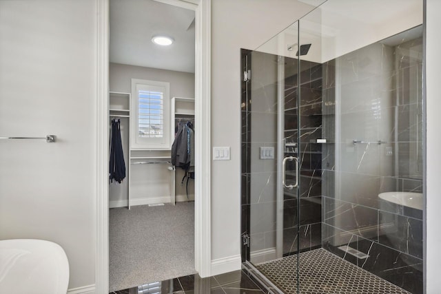 full bath with a stall shower, a walk in closet, and baseboards