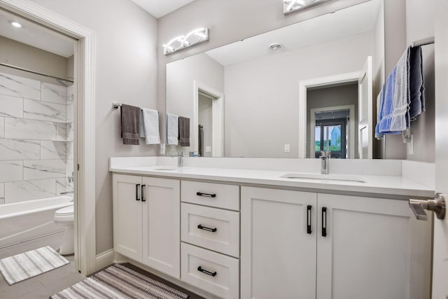 bathroom featuring double vanity, toilet, shower / bathing tub combination, and a sink