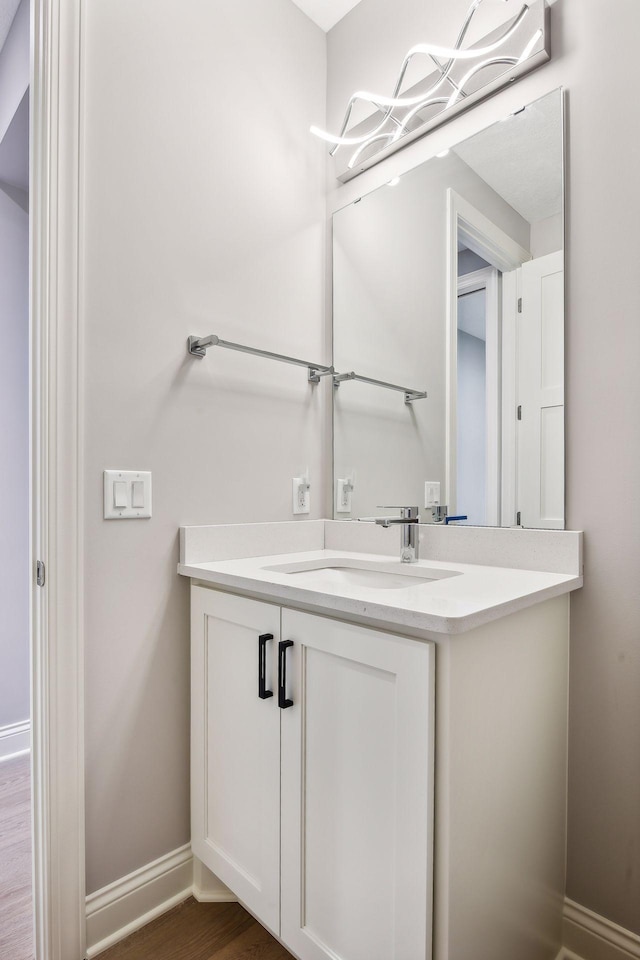 bathroom featuring vanity, wood finished floors, and baseboards