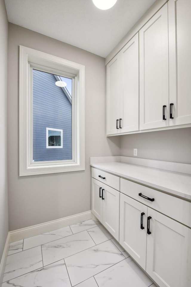 laundry area with baseboards and marble finish floor