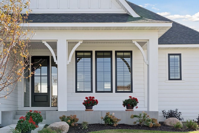 doorway to property featuring board and batten siding and roof with shingles