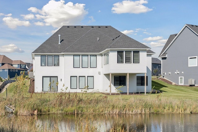 rear view of house featuring a water view and a shingled roof