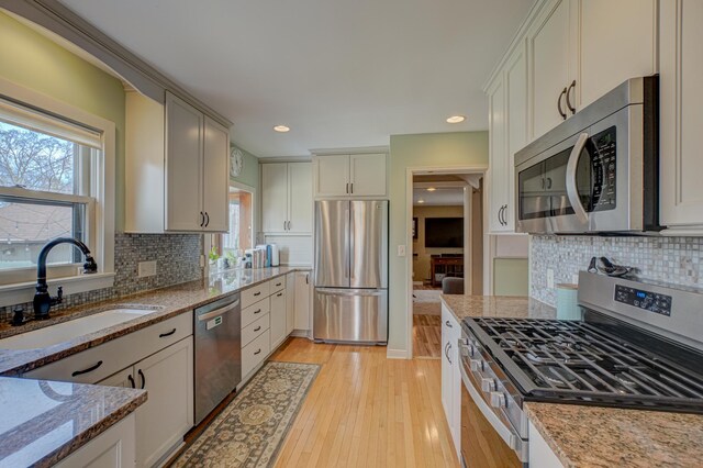 5920 Colfax Ave S, Minneapolis, MN 55419 - kitchen with stainless steel appliances, light stone countertops, a sink, and light wood-type flooring