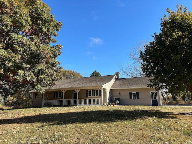 single story home featuring a porch, a chimney, and a front lawn