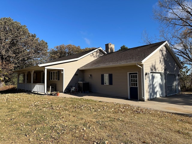 back of property with central AC, covered porch, roof with shingles, an attached garage, and a chimney