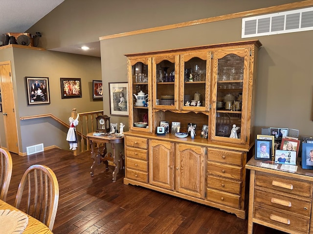 bar featuring dark wood finished floors, vaulted ceiling, and visible vents