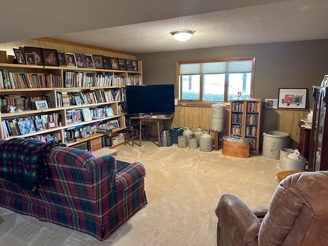 living area with a wainscoted wall, carpet floors, a textured ceiling, and wood walls