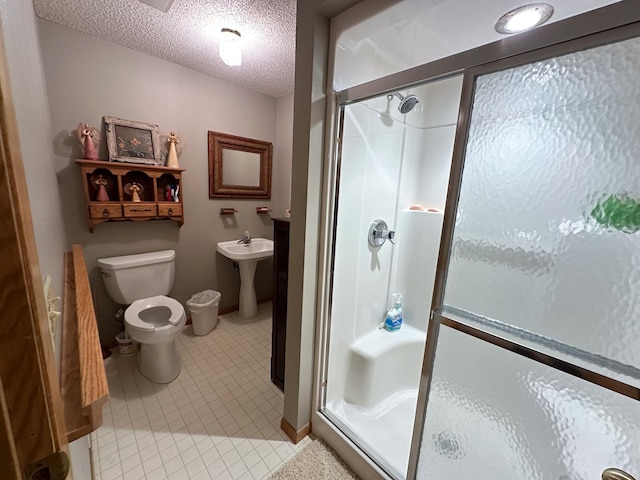 bathroom featuring toilet, a stall shower, tile patterned flooring, and a textured ceiling