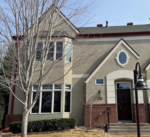 view of front of property featuring brick siding and stucco siding