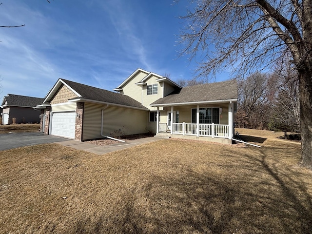 view of front facade with a front yard, a garage, covered porch, and driveway