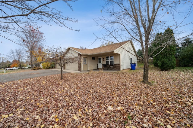 exterior space featuring brick siding, covered porch, an attached garage, and driveway