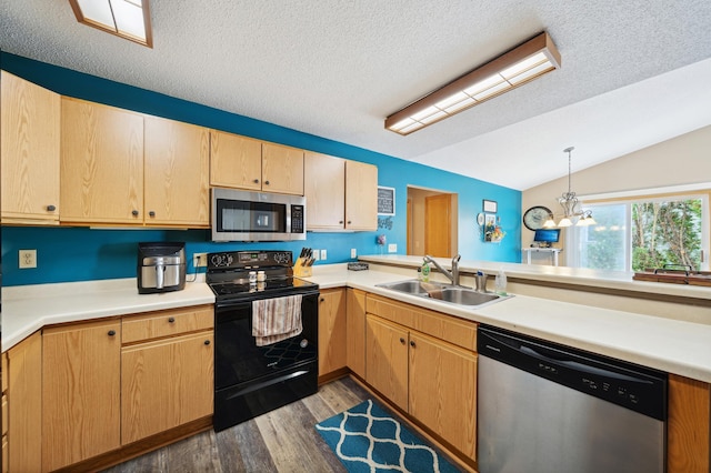 kitchen featuring wood finished floors, a sink, stainless steel appliances, vaulted ceiling, and light countertops