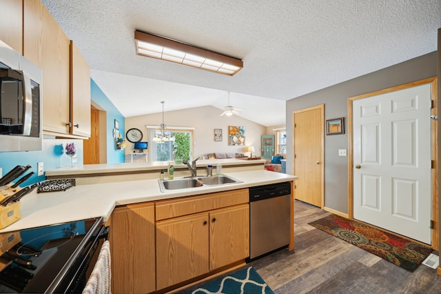 kitchen with a sink, wood finished floors, stainless steel appliances, a peninsula, and vaulted ceiling