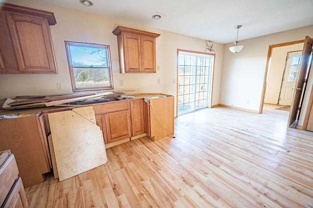 kitchen with decorative light fixtures, light countertops, recessed lighting, brown cabinets, and light wood-style floors