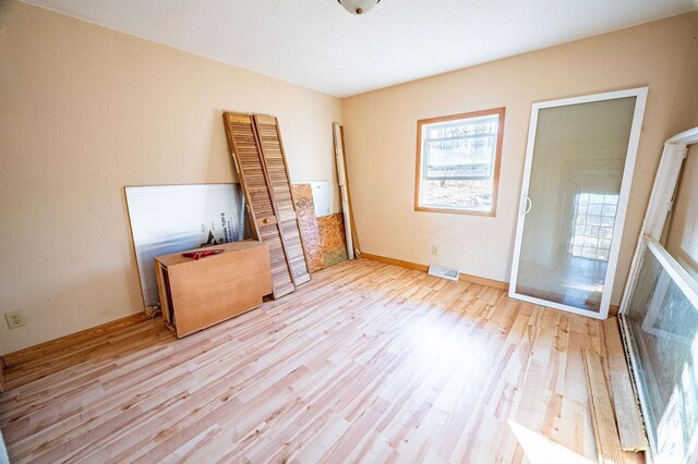 unfurnished bedroom with wood finished floors, visible vents, and baseboards