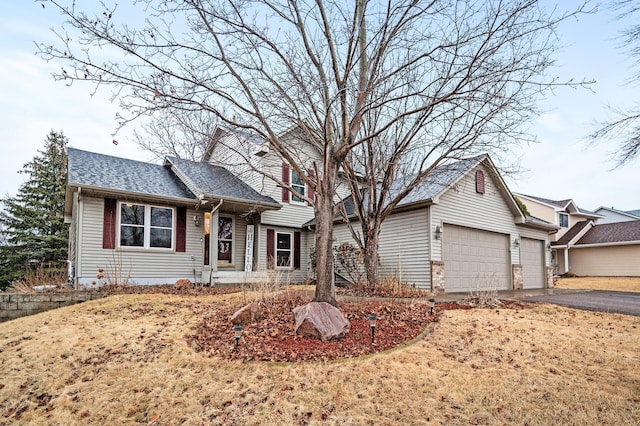 split level home featuring aphalt driveway, a garage, and a shingled roof