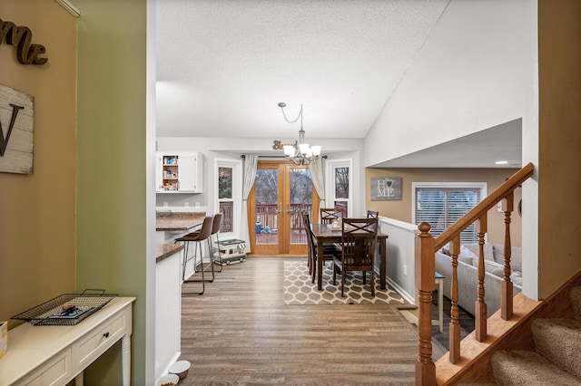 dining room featuring lofted ceiling, stairs, an inviting chandelier, and wood finished floors