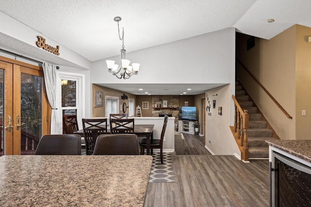 dining area with stairway, dark wood-style floors, a chandelier, and vaulted ceiling